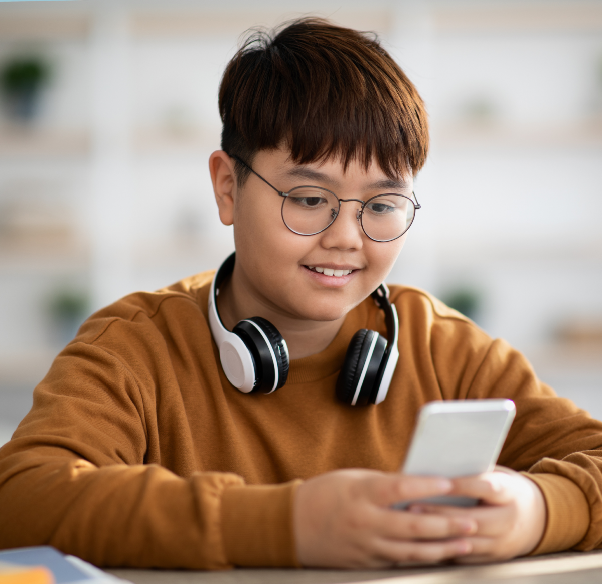 Picture of a student with headphones holding a mobile device.