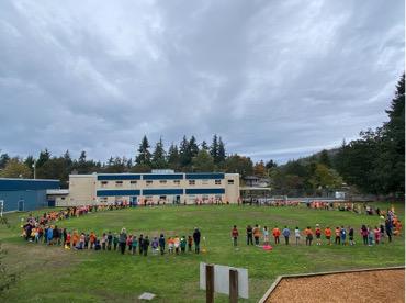 Students standing in a large circle in a field